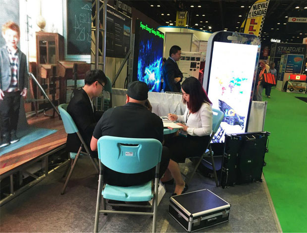 奥兰多橘城会展中心米兰milan展位现场，外贸部经理黄勇强和何巧玲与意向客户在交谈中